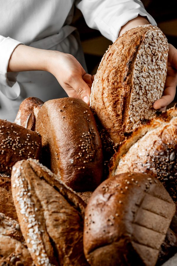 woman putting whole grain bread bun among other breads